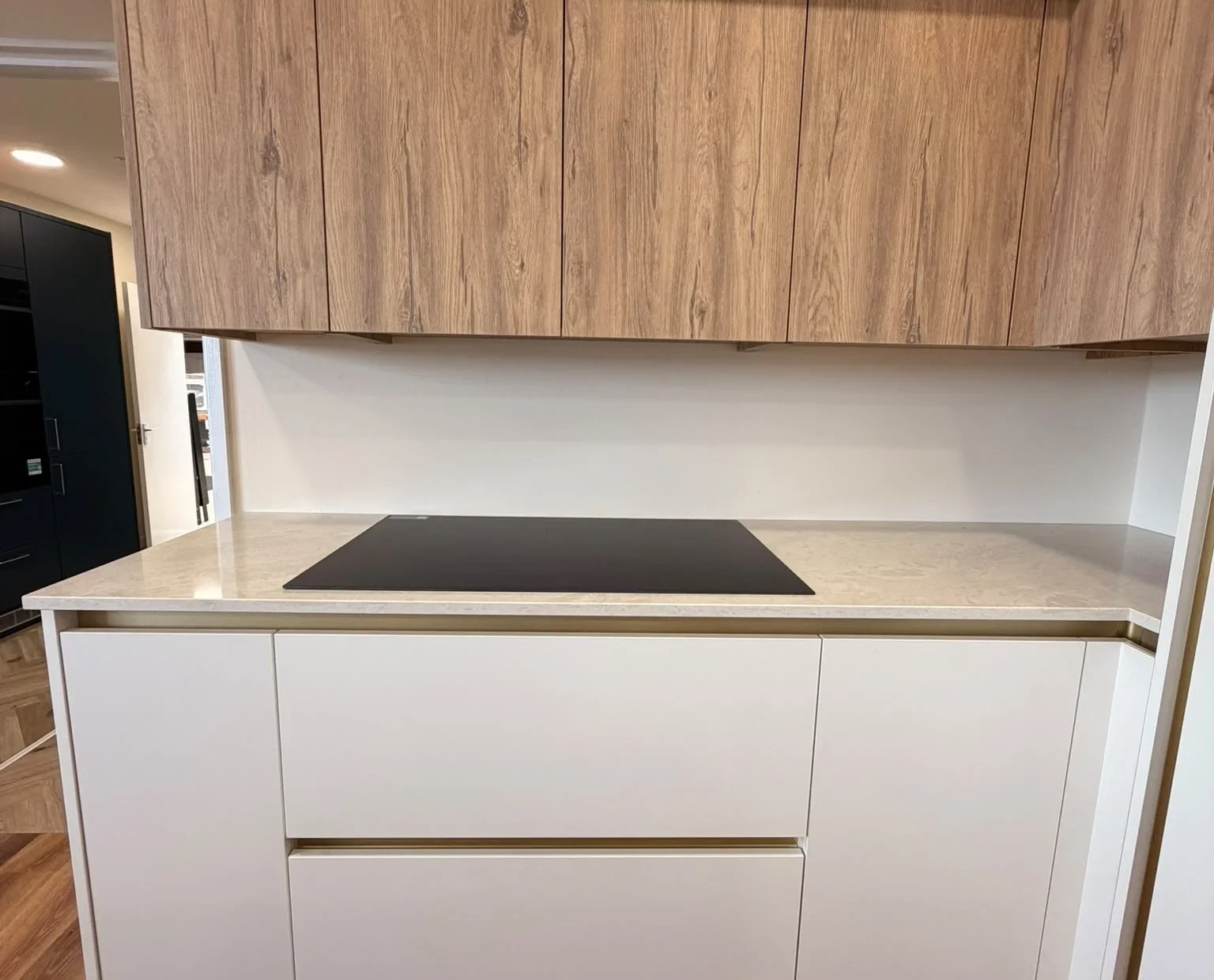 Induction hob on a cream handleless kitchen run with oak-effect wall units