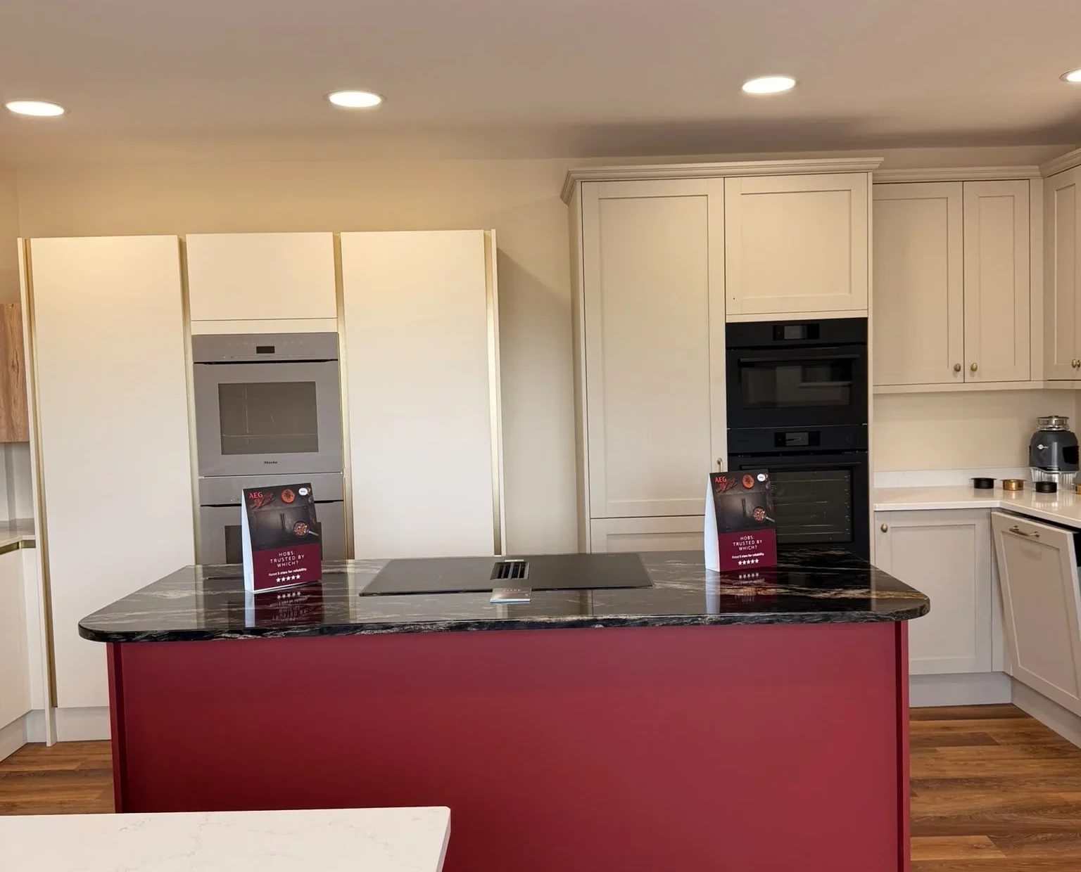 Bristol Appliance Centre showroom kitchen with a red island, dark granite worktop and built-in ovens